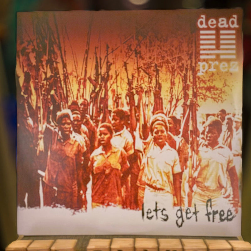 Album cover with text 'lets get free' and a 'NOW PLAYING' sign below.