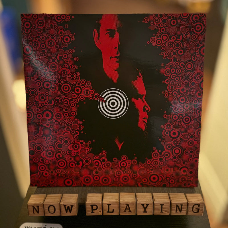 Small wooden box with a red and black design and 'Now Playing' stamps on top.
